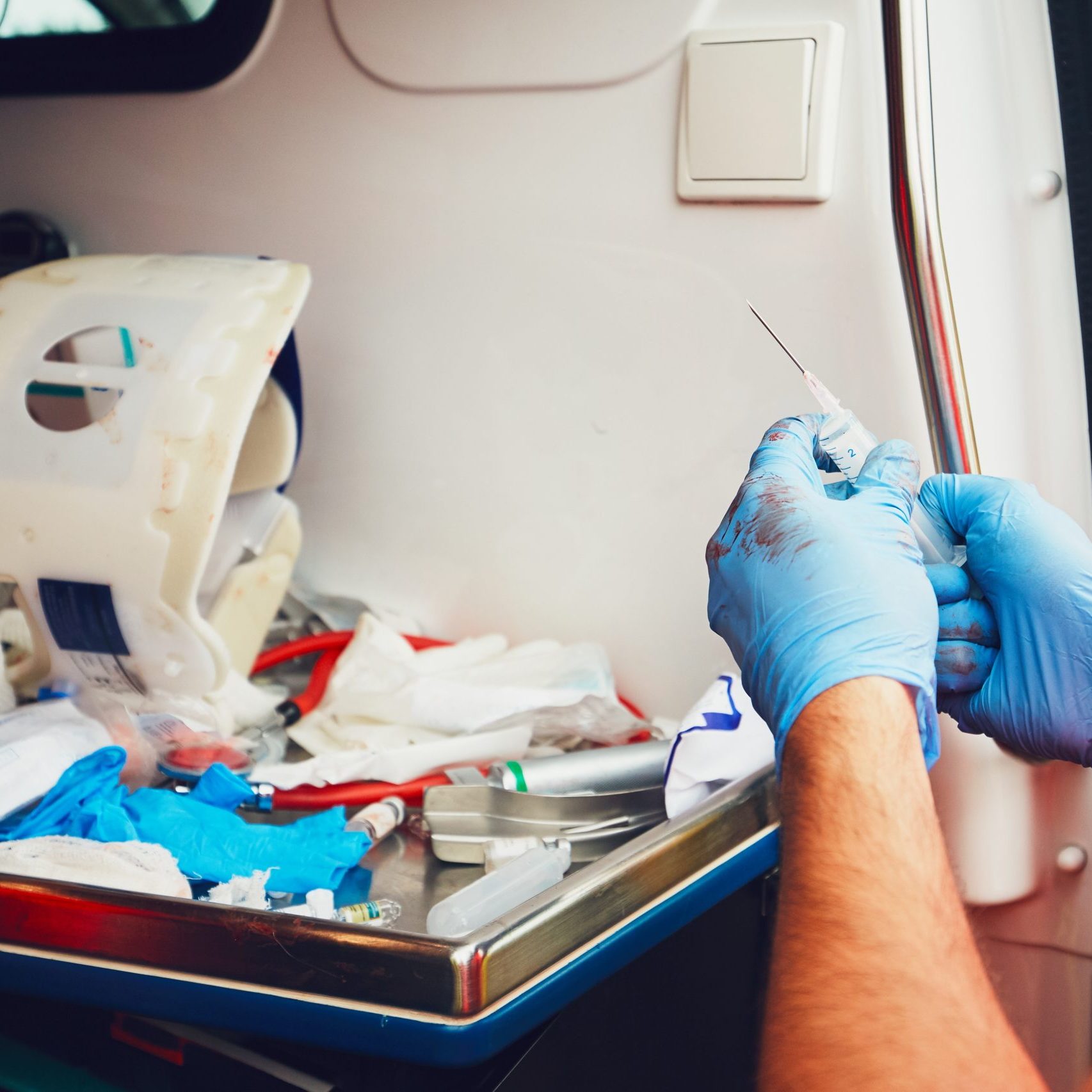 Paramedic in door of the ambulance car prepares medicines for an injured patient (detail of the hands). Theme of the rescue, help and hope.